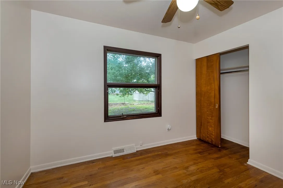 Bedroom with hardwood flooring, ceiling fan, and a closet
