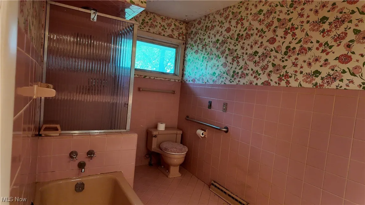 Bathroom with wallpapered walls, tile walls, tile patterned floors, a bath, and a baseboard radiator
