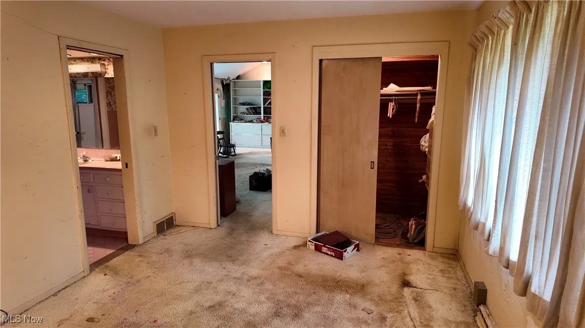 Unfurnished bedroom with carpet floors, connected bathroom, and a closet