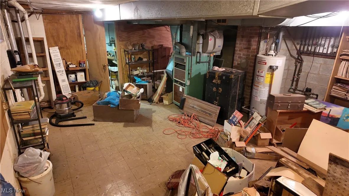 Unfinished below grade area featuring tile patterned floors and water heater