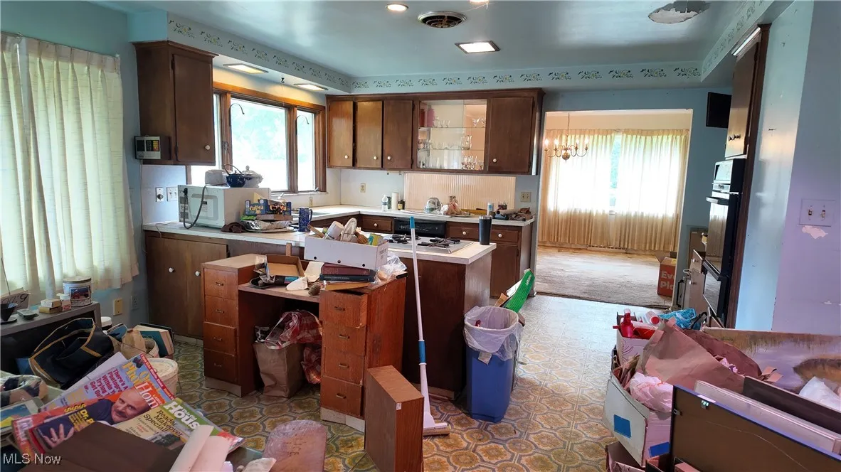 Kitchen with light countertops, healthy amount of natural light, dark brown cabinetry, and a chandelier