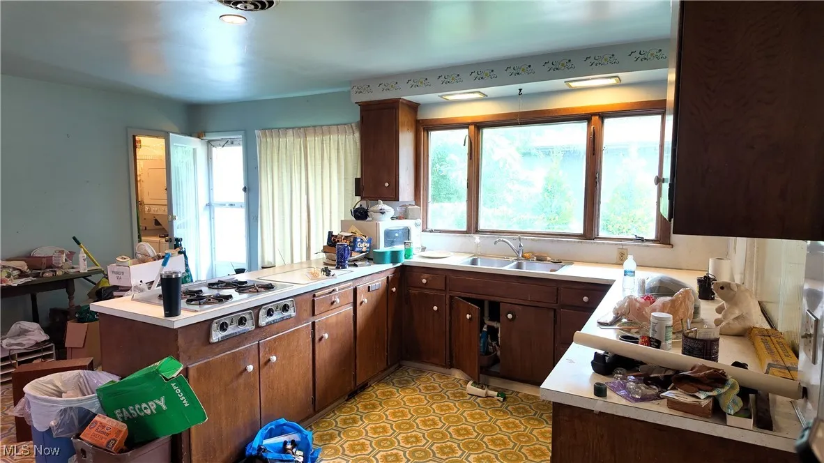 Kitchen with a peninsula, light countertops, dark brown cabinets, and white gas cooktop