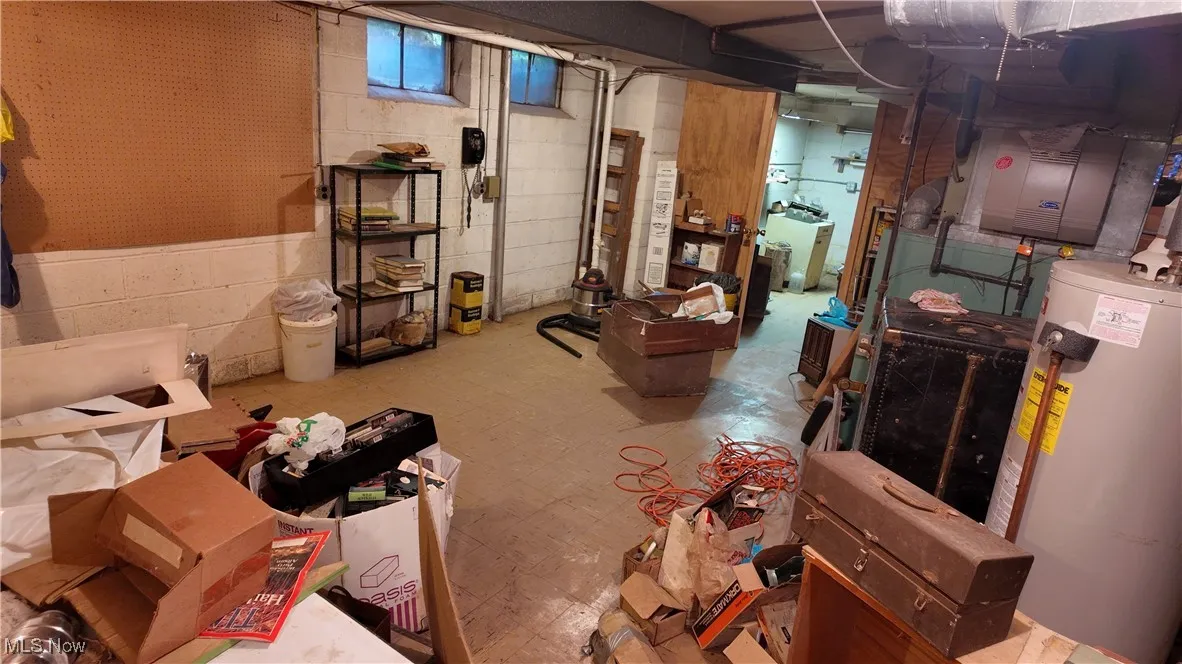 Below grade area with water heater and tile patterned floors