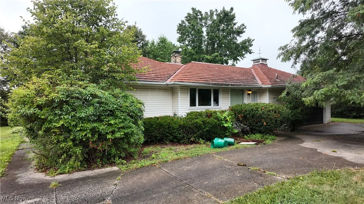 View of front of property with a chimney, driveway, and a garage