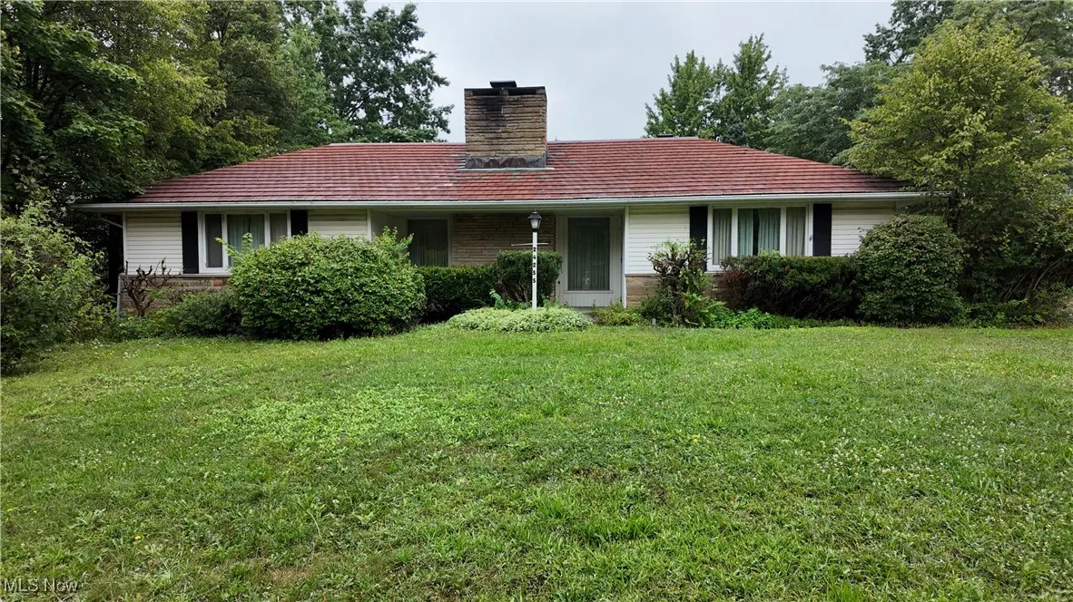 View of front facade with a front lawn, a chimney, and brick siding
