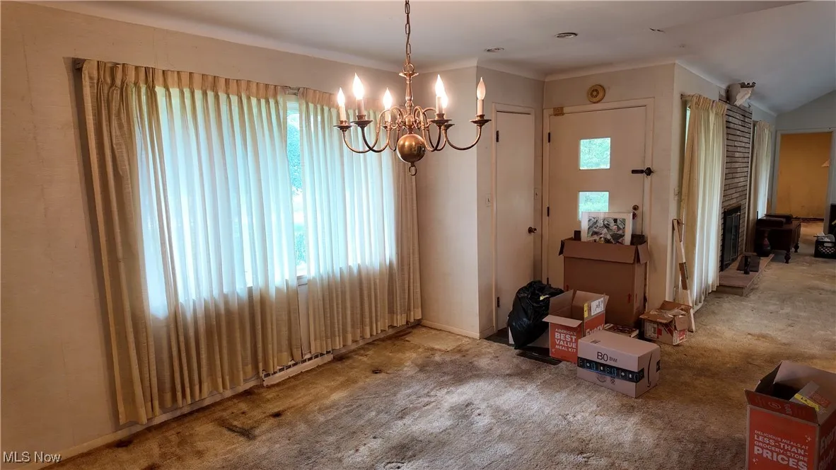 Carpeted dining space with healthy amount of natural light and a chandelier