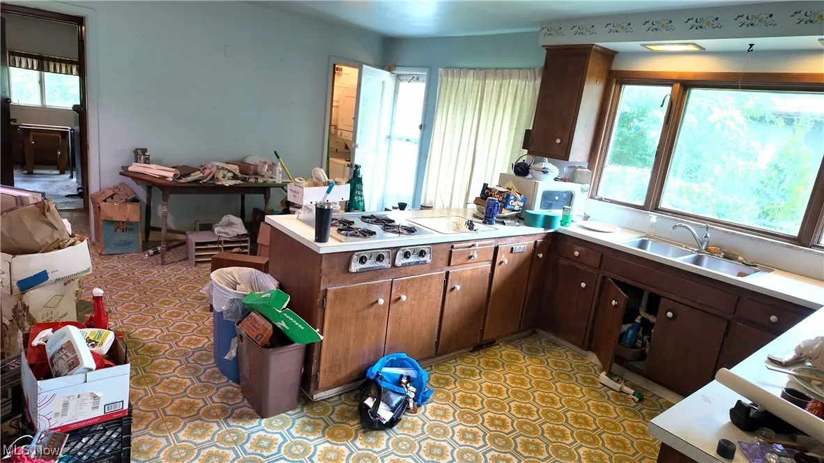 Kitchen featuring a peninsula, dark brown cabinets, and light countertops