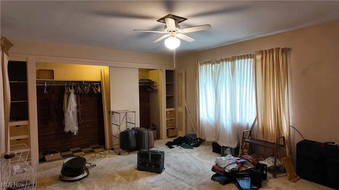 Carpeted bedroom featuring a ceiling fan and multiple closets