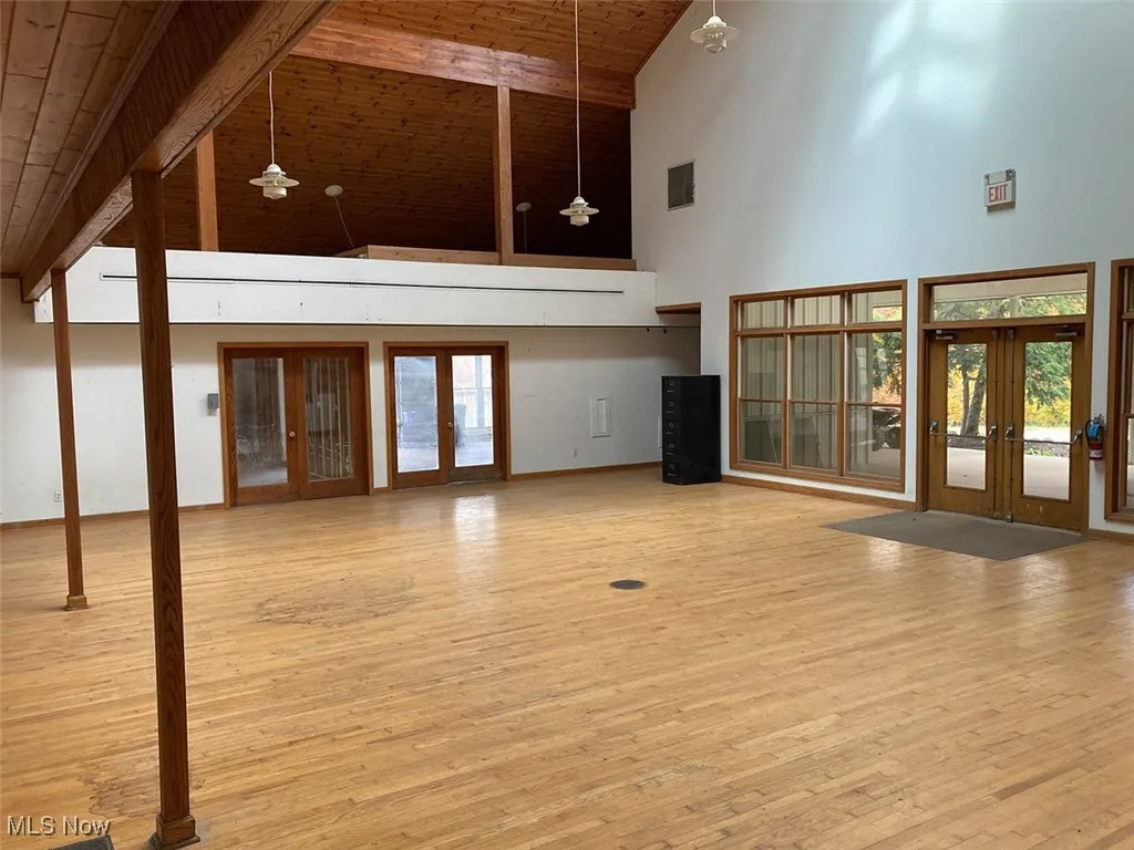 Unfurnished living room featuring french doors, light wood-style floors, high vaulted ceiling, a wood ceiling with exposed beams, and ceiling fan