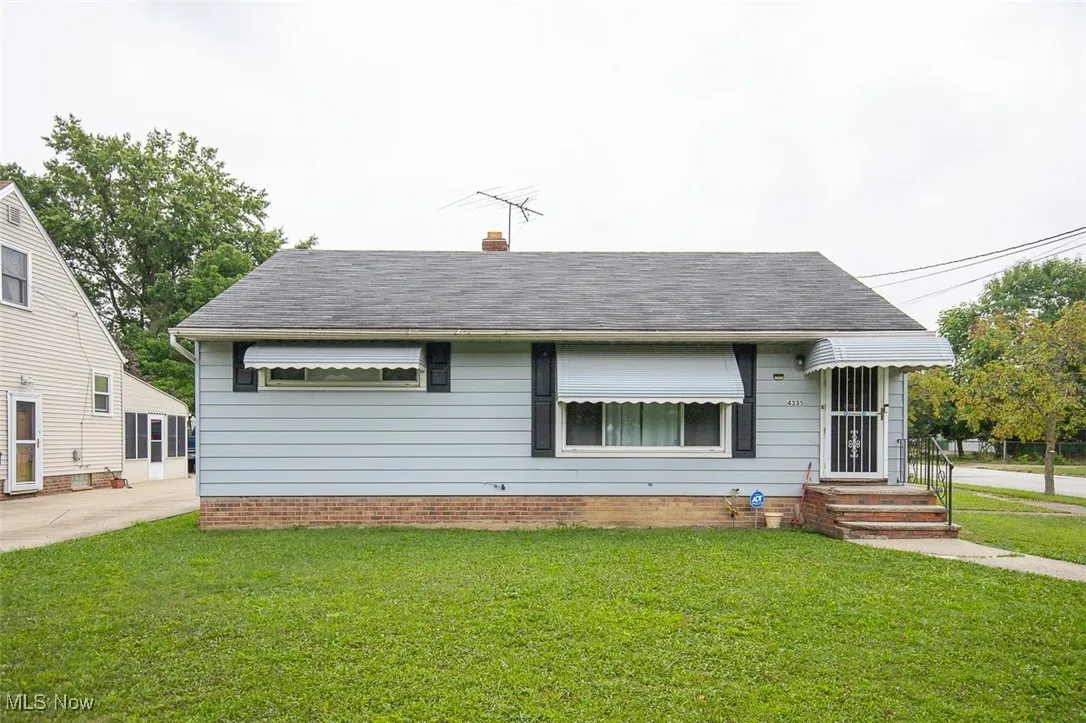 View of front of home featuring a front yard, a chimney, and roof with shingles