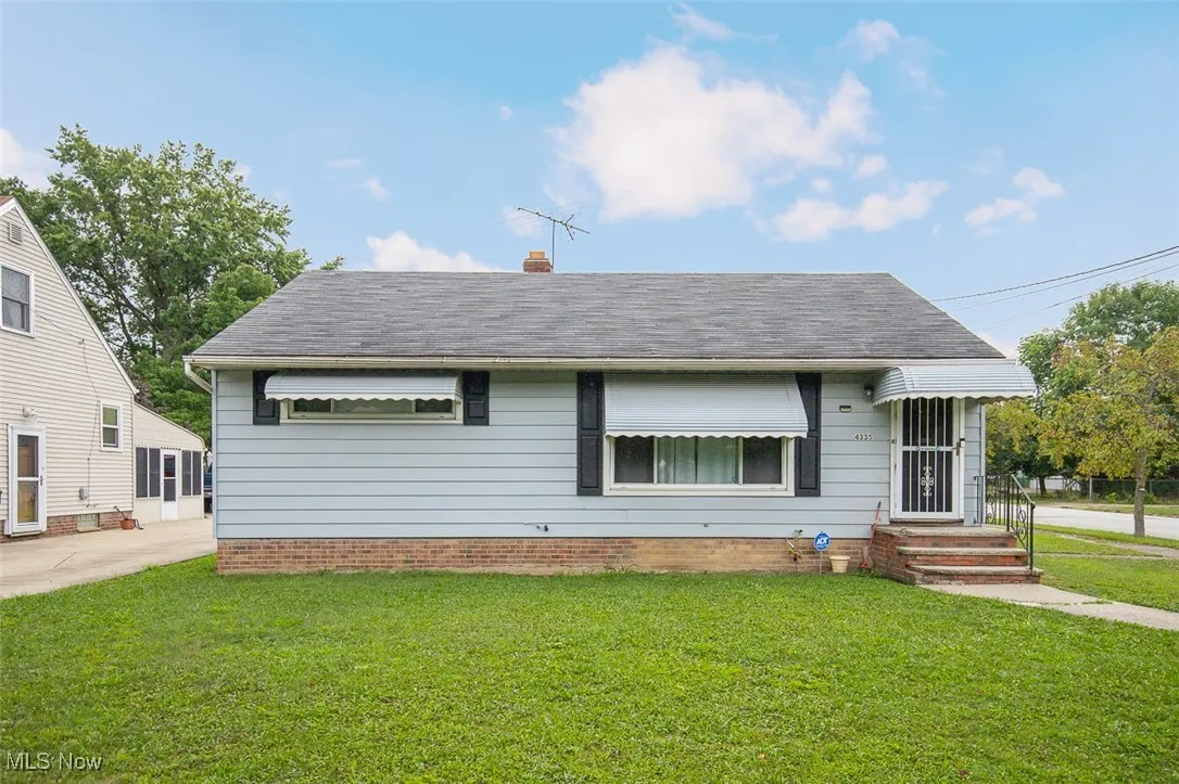 View of front of house featuring a front lawn, a shingled roof, and a chimney