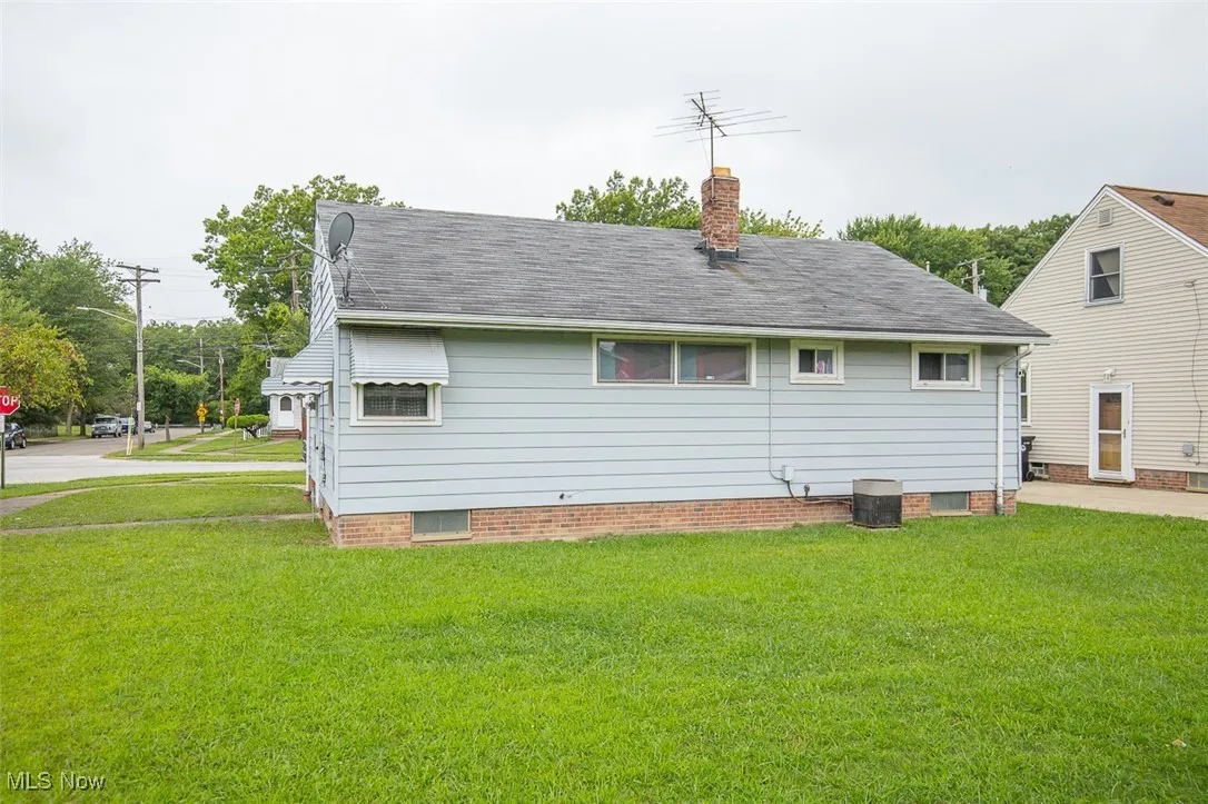 Back of house with a chimney, a yard, and a shingled roof
