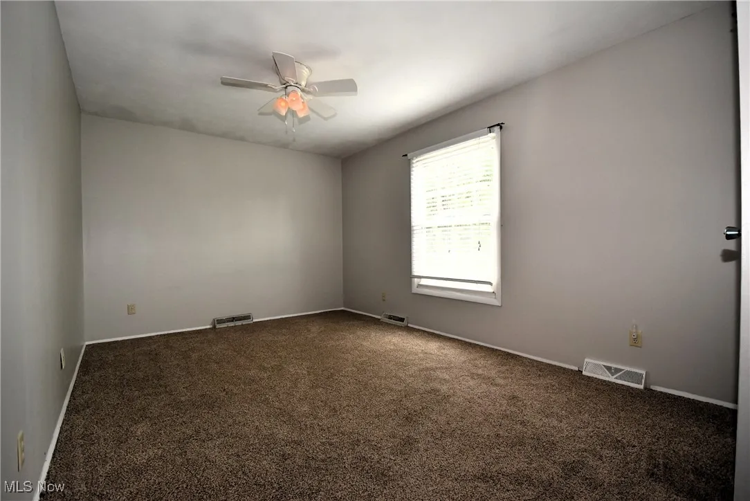 Carpeted spare room with baseboards and ceiling fan