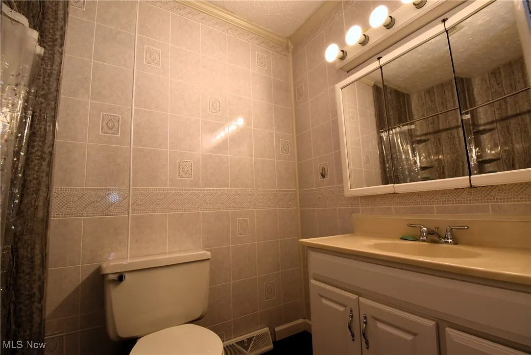 Bathroom with tile walls, vanity, and a shower with curtain