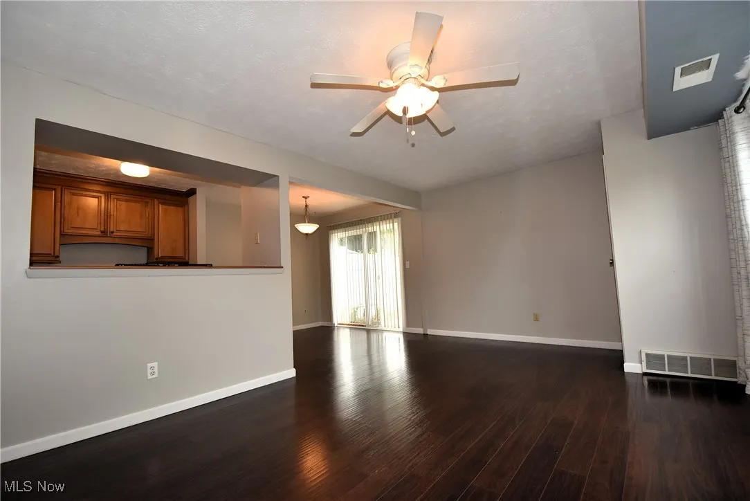 Unfurnished living room with dark wood-type flooring, ceiling fan, and a textured ceiling