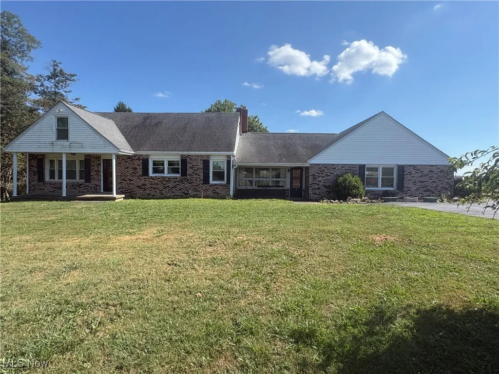 View of front of home with a front lawn, brick siding, and a chimney