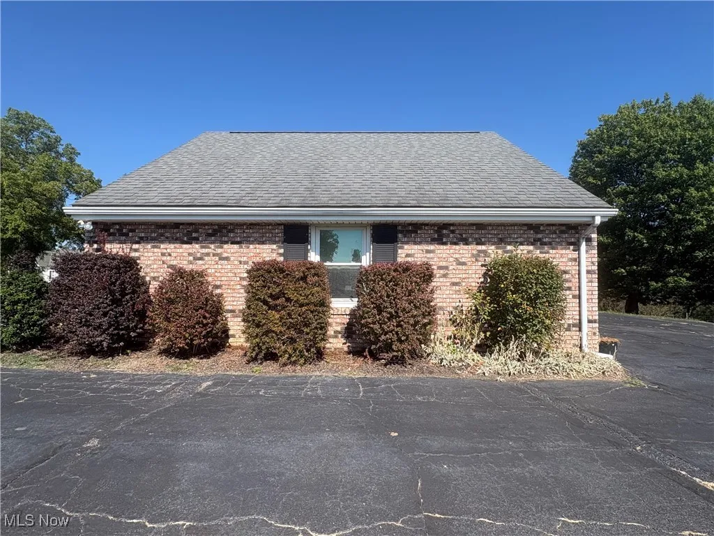 View of property exterior featuring brick siding and roof with shingles