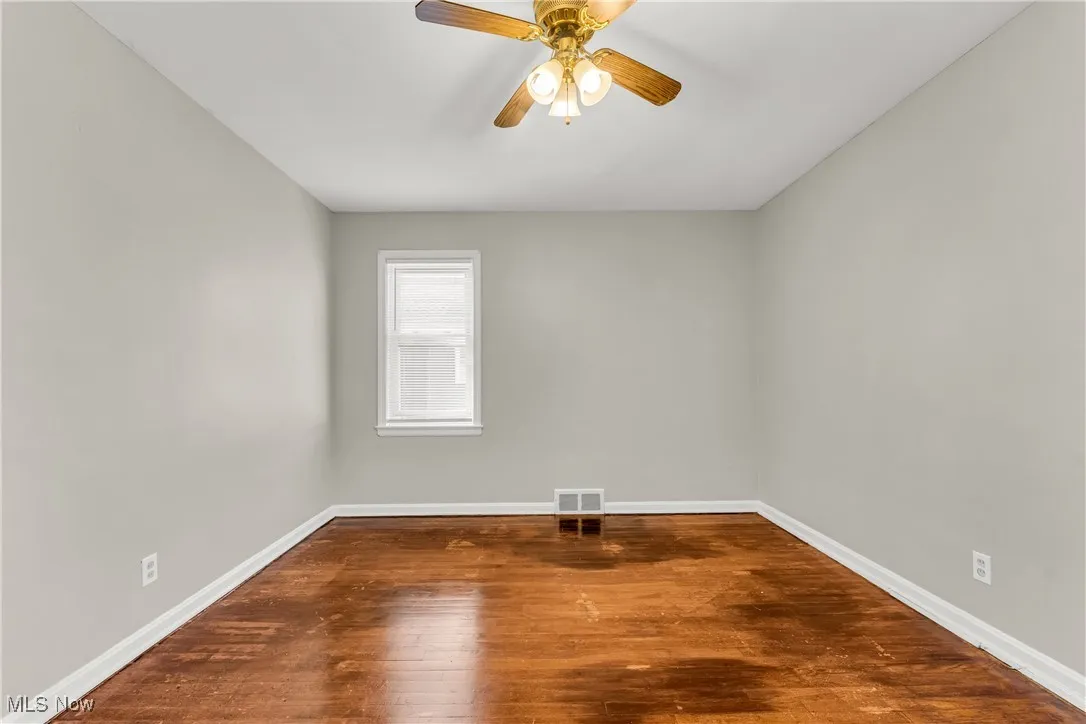 Empty room featuring dark wood-type flooring and ceiling fan