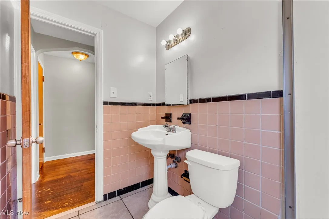 Bathroom with tile walls, tile patterned flooring, and wainscoting