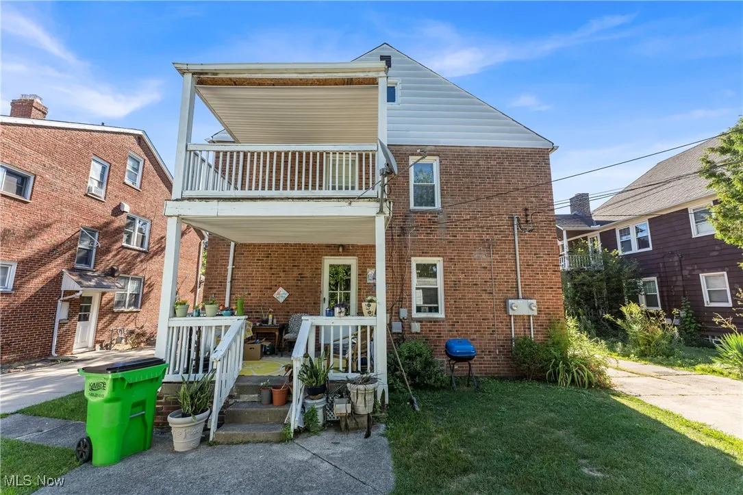 Rear view of property featuring brick siding, a patio, and a lawn