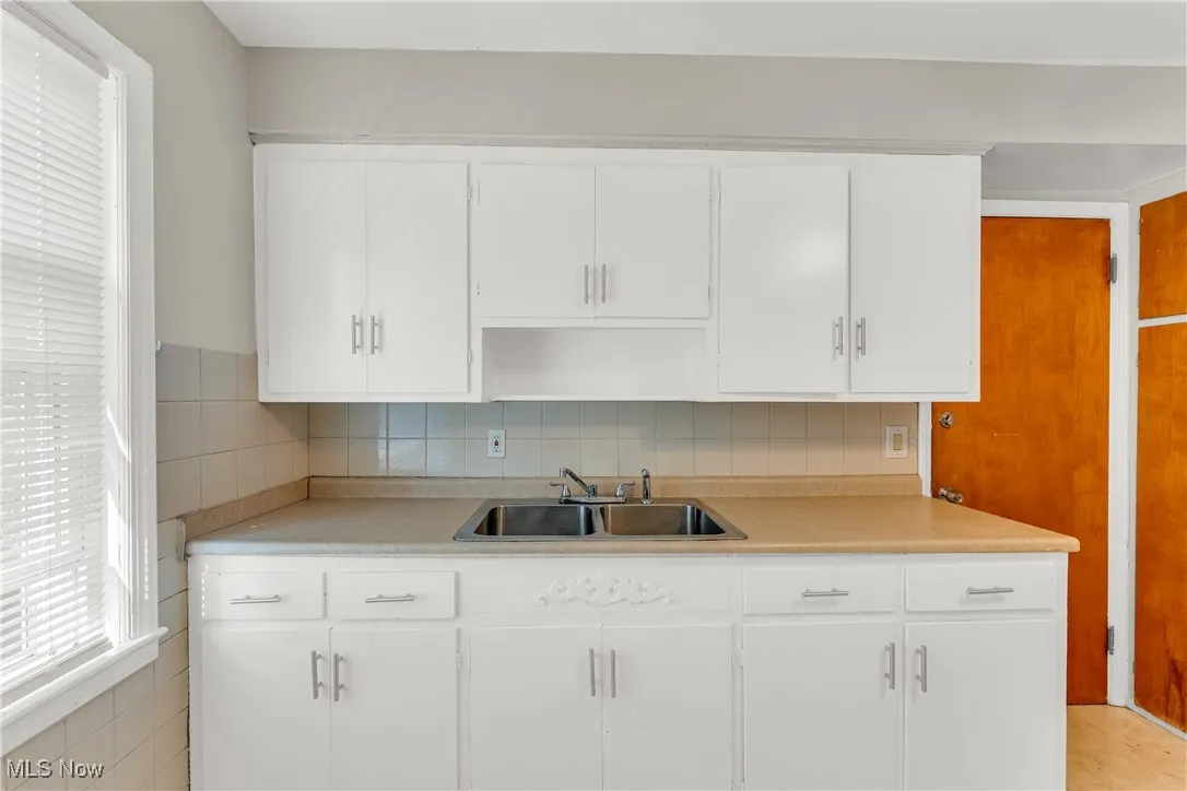 Kitchen with white cabinetry, light countertops, and tasteful backsplash