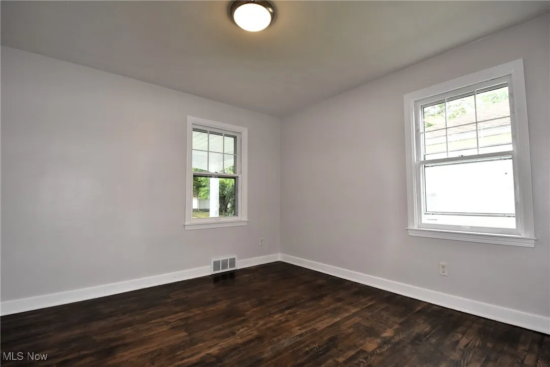 Empty room featuring dark wood-style flooring and baseboards