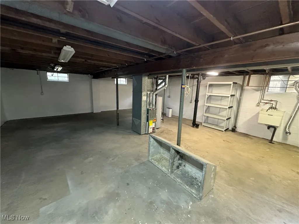 Below grade area with heating unit, plenty of natural light, and gas water heater