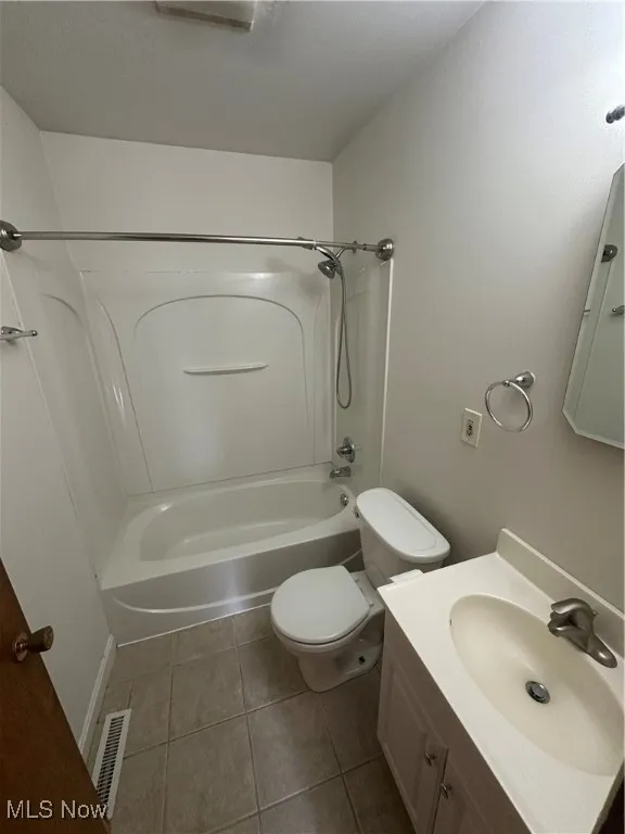 Full bath with shower / bath combination, dark tile patterned flooring, and vanity