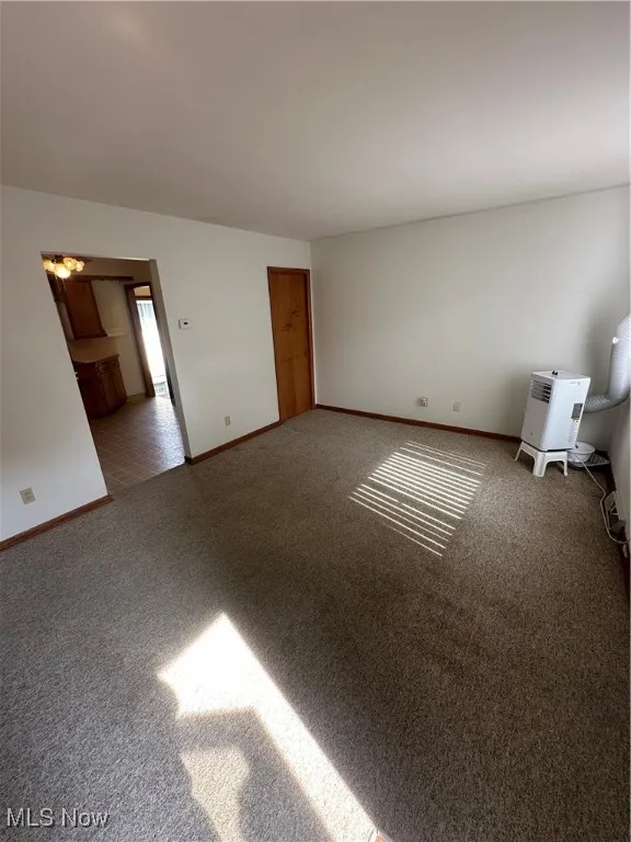 Carpeted spare room with baseboards