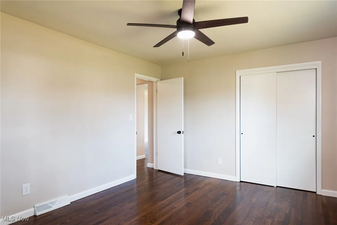 Unfurnished bedroom featuring dark wood finished floors, a ceiling fan, and a closet