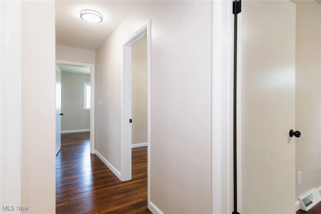 Hall featuring dark wood-type flooring and baseboards