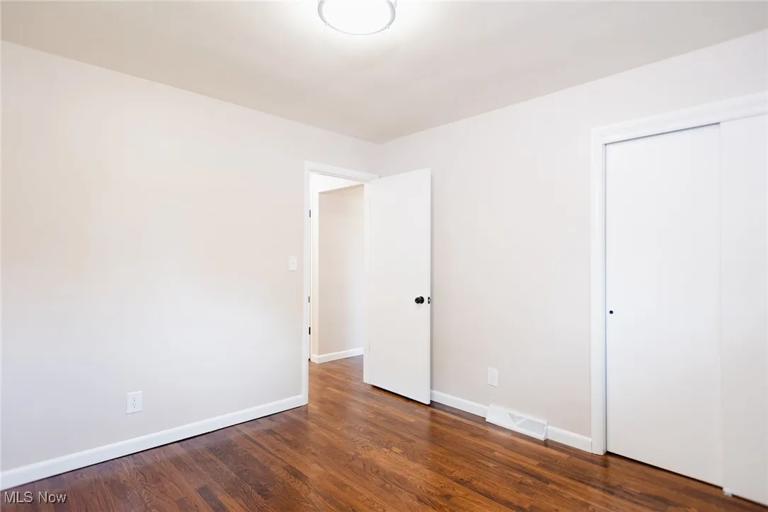 Unfurnished bedroom with dark wood-style floors and a closet