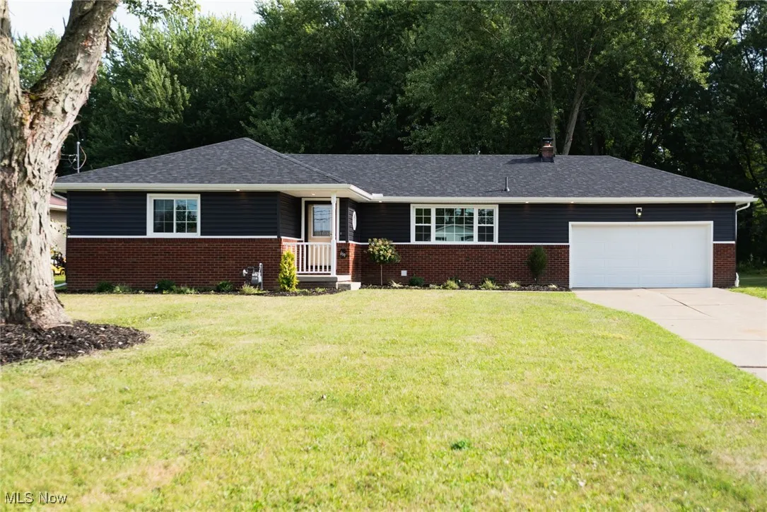 Single story home with driveway, an attached garage, a front yard, and brick siding