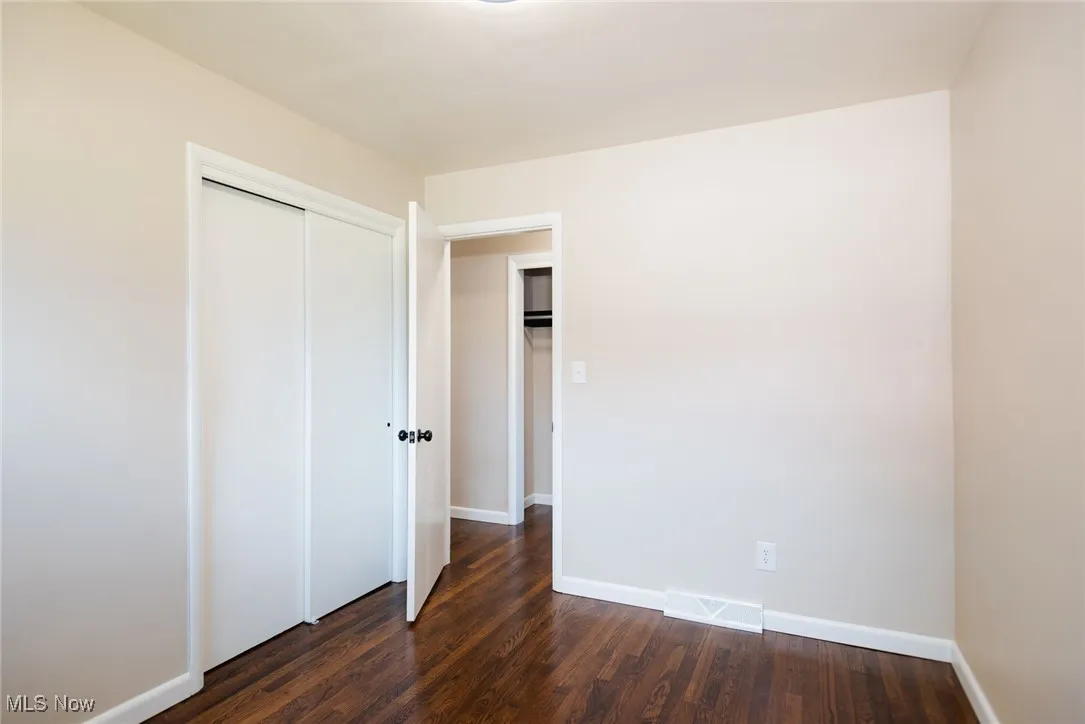Unfurnished bedroom featuring dark wood-style flooring and a closet