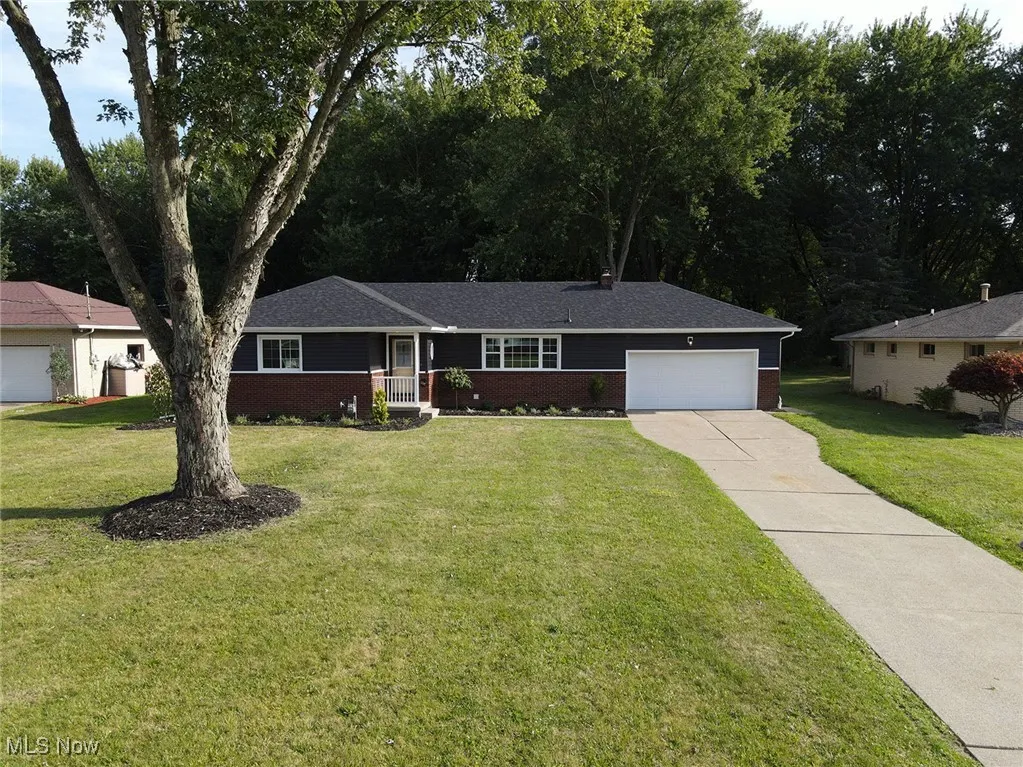 Single story home with brick siding, concrete driveway, a garage, and a front yard