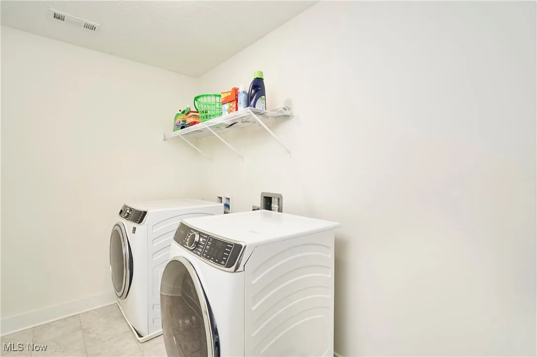 Laundry area featuring light tile patterned floors and washer and dryer