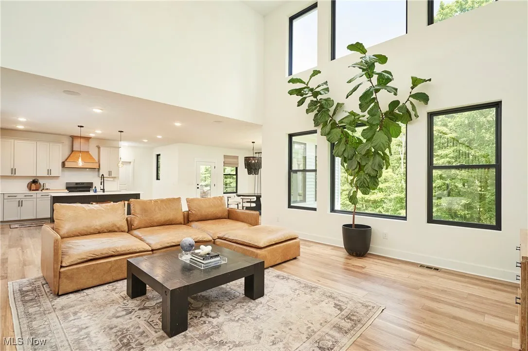 Living room featuring a high ceiling, light wood finished floors, and recessed lighting