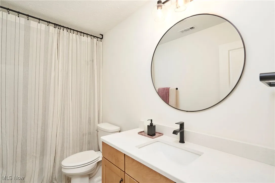 Full bathroom with vanity, a textured ceiling, and a shower with curtain