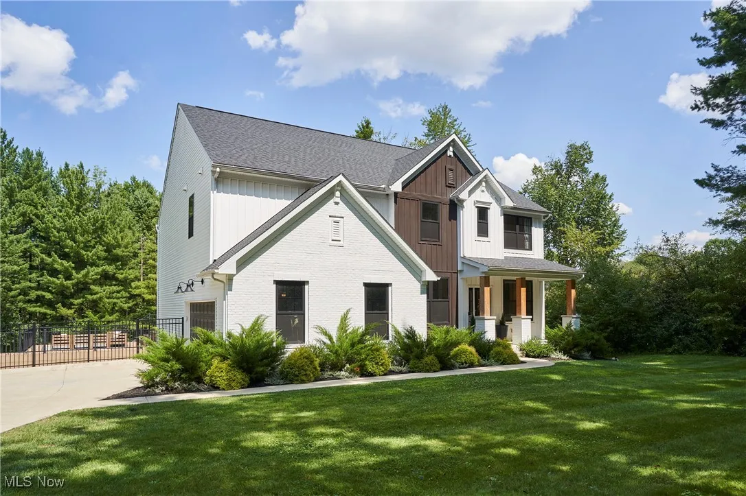 Modern farmhouse style home with a garage, a porch, driveway, roof with shingles, and brick siding