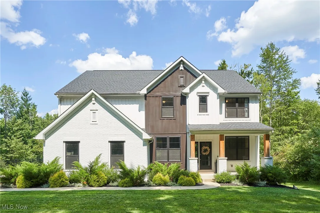 Modern farmhouse style home featuring a porch, a front lawn, brick siding, and roof with shingles