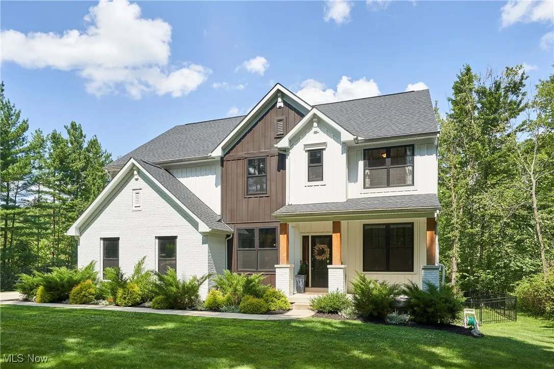 Modern inspired farmhouse with covered porch, a front lawn, a shingled roof, and brick siding