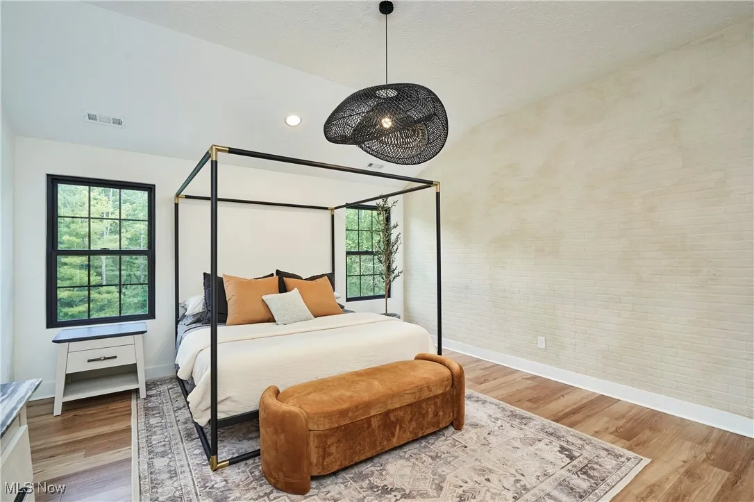 Bedroom with vaulted ceiling, wood finished floors, and a textured ceiling