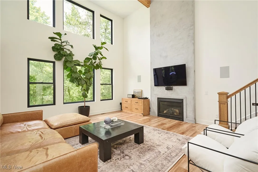 Living area with wood finished floors, a fireplace, plenty of natural light, a towering ceiling, and beamed ceiling
