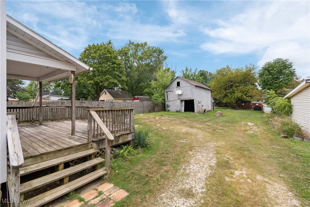 Fenced backyard with a deck, an outbuilding, and a detached garage