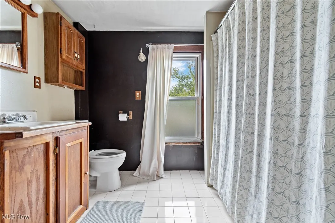 Bathroom with vanity, light tile patterned floors, and curtained shower