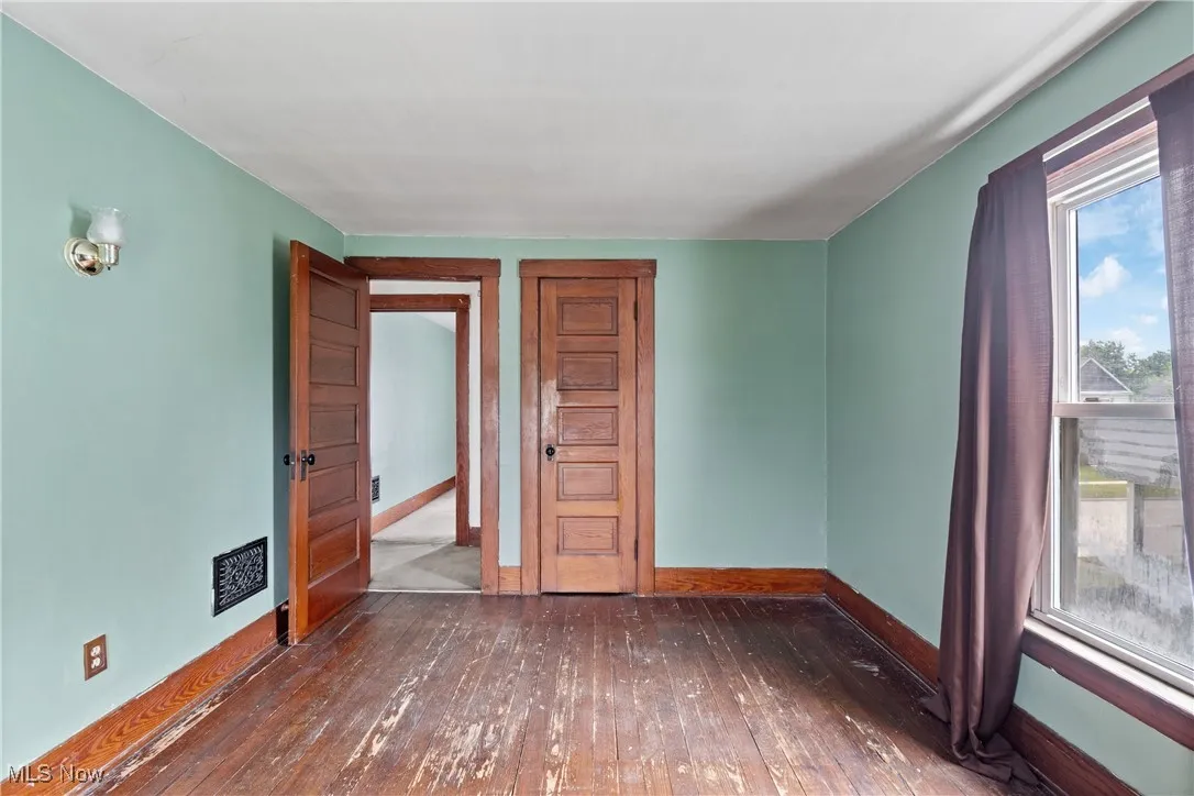 Spare room featuring dark wood-style flooring and baseboards