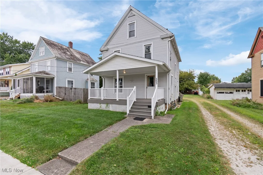 American foursquare style home with driveway, covered porch, an outbuilding, a garage, and a sunroom