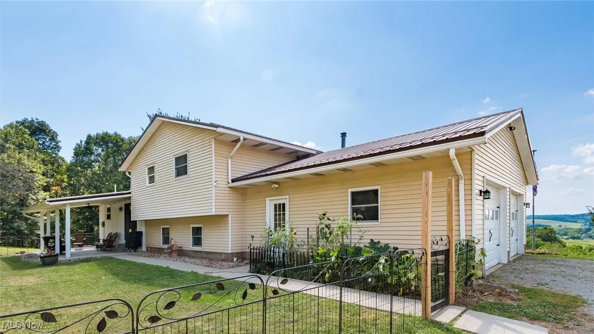 Back of house with a metal roof, a patio area, and a garage