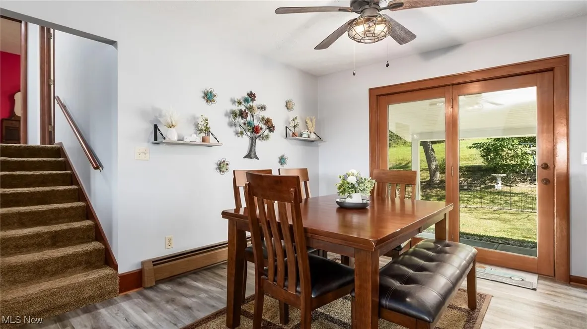 Dining room with wood finished floors, ceiling fan, and stairway