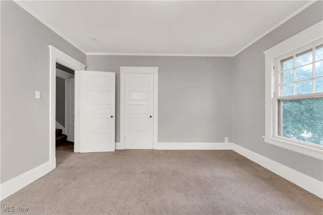 Unfurnished bedroom with carpet, crown molding, and a closet